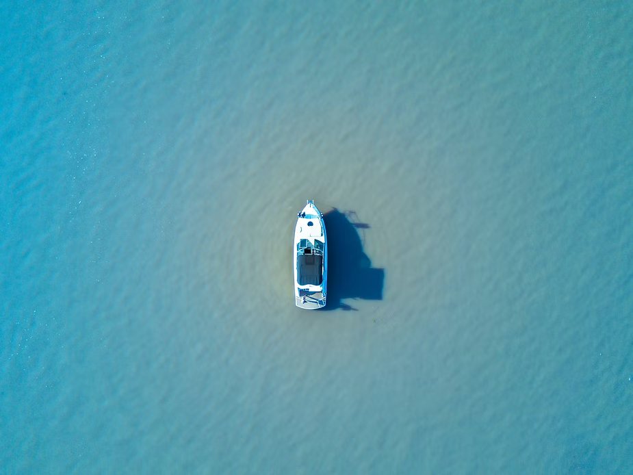 Vista aérea de um pequeno barco branco parado em águas azul-turquesa