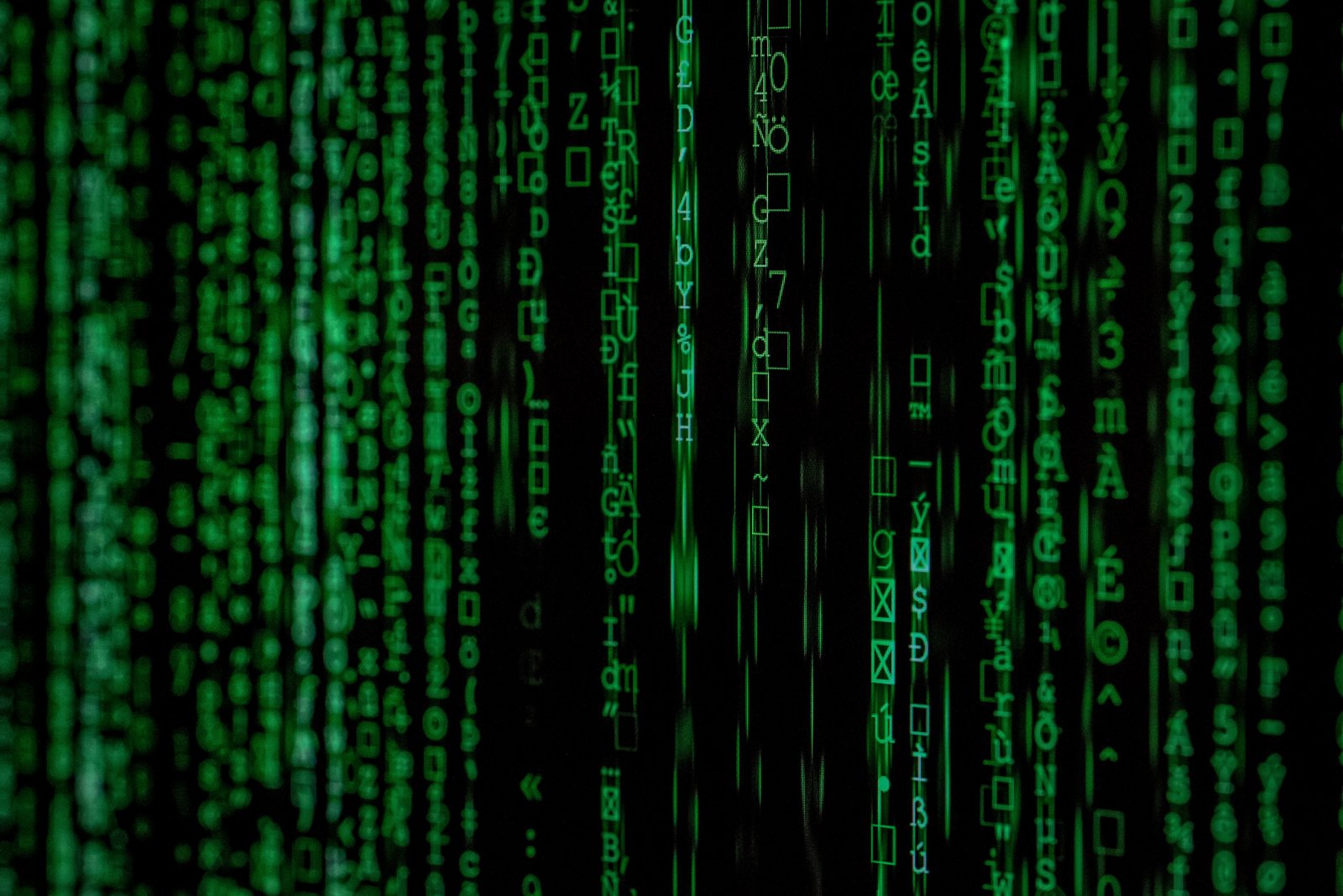 Colunas verticais de caracteres verdes sobre fundo preto, no estilo do código digital de Matrix